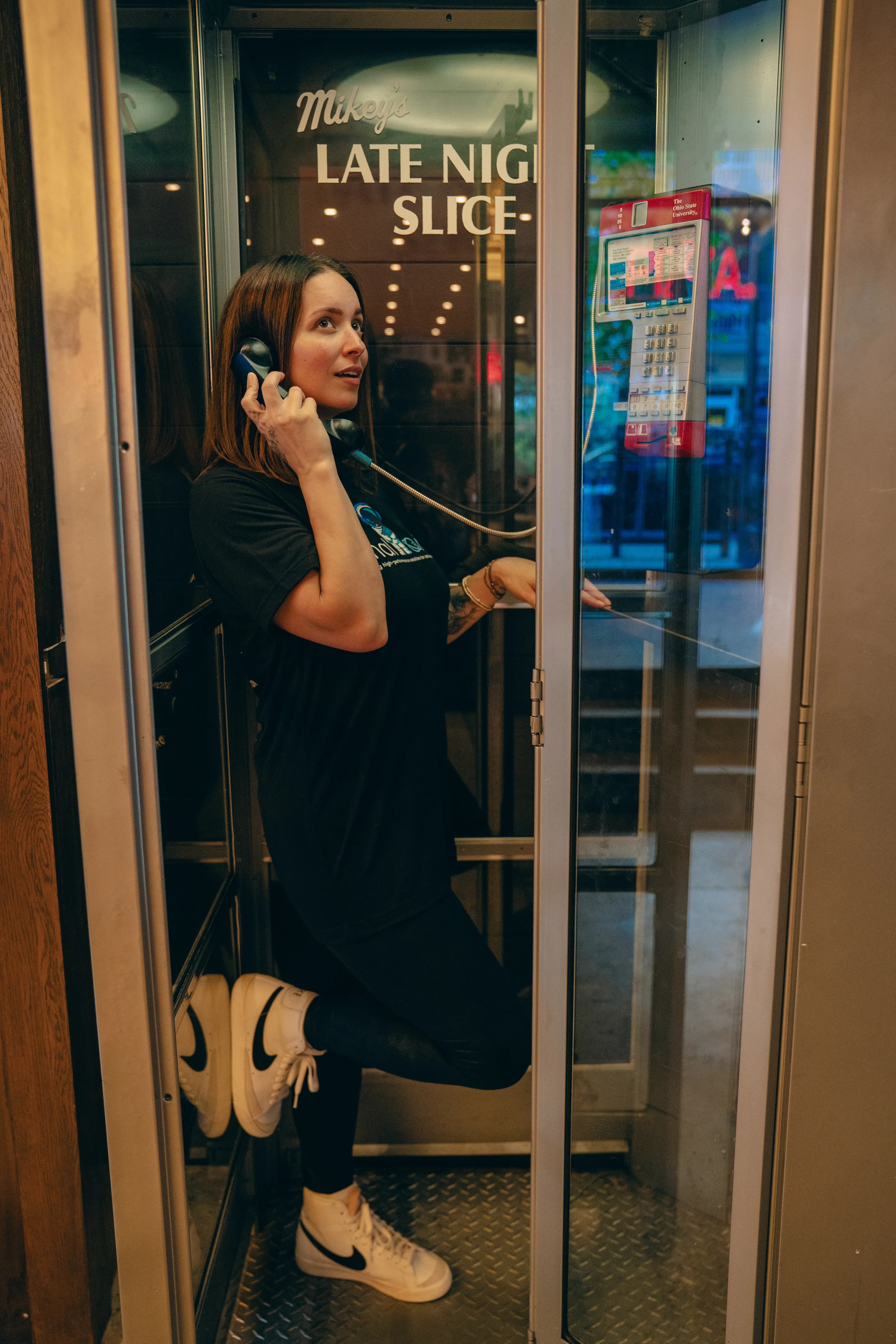 Team member in a Mikey's Late Night Slice phone booth wearing a Final Orbit shirt